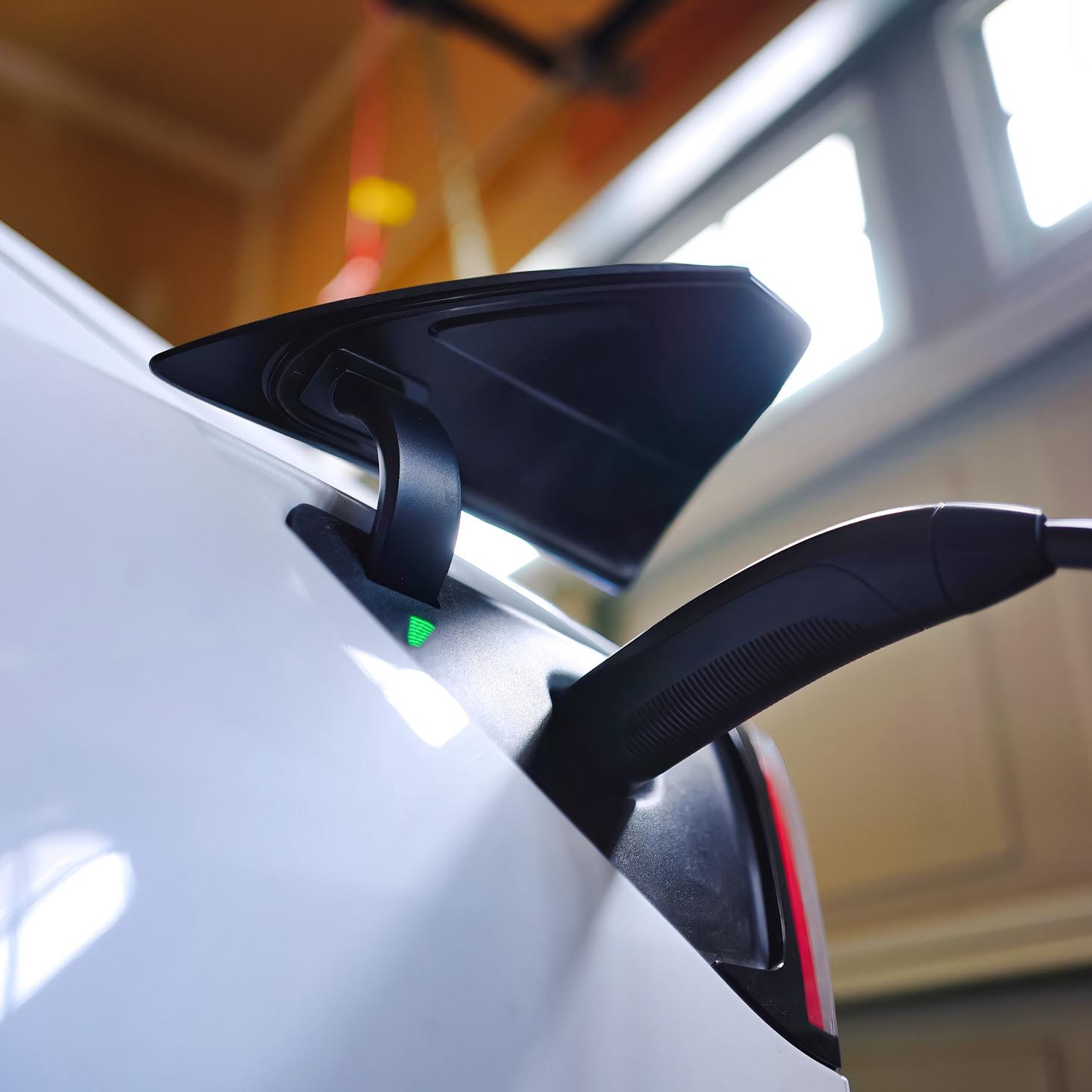 White EV electric car plugged and charging inside garage at home